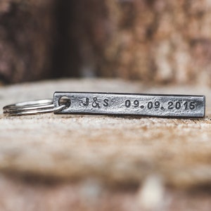 May include: A silver metal keychain with a rectangular tag engraved with "J&S 09.09.2015".