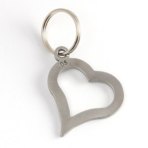 May include: A silver heart-shaped keychain with a ring attached. The keychain has the initials "DS" engraved on the back.