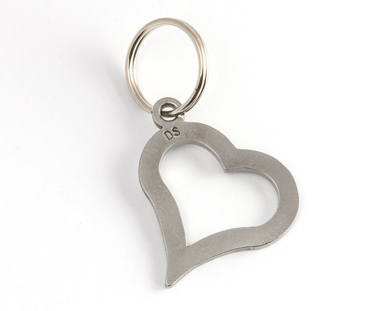 May include: A silver heart-shaped keychain with a ring attached. The keychain has the initials "DS" engraved on the back.