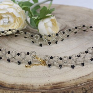 May include: A delicate silver choker necklace with black beads. The necklace has a delicate, intricate design and is perfect for adding a touch of elegance to any outfit.