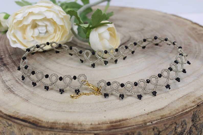 May include: A delicate silver choker necklace with black beads. The necklace has a delicate, intricate design and is perfect for adding a touch of elegance to any outfit.