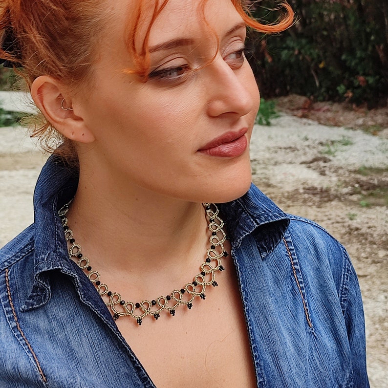 May include: A woman with red hair wearing a denim shirt and a gold and black beaded necklace.