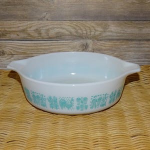 May include: White casserole dish with blue and green Pennsylvania Dutch folk art design. The dish has two handles.