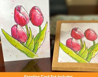 Könnte beinhalten: Ein Grußkartenset mit Aquarellillustrationen von roten Tulpen und grünen Blättern. Die Karten werden in einer braunen Schachtel und einzeln präsentiert. Der Text auf dem Bild lautet: Grußkartenset enthält 8 Karten und Umschläge!