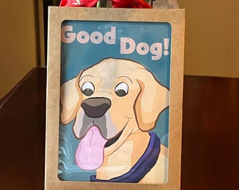 May include: A framed print with a cartoon illustration of a golden Labrador Retriever with its tongue out. The text "Good Dog!" is printed above the dog. The frame is made of brown cardboard.