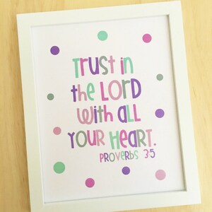 May include: A framed print with a white background and colorful polka dots. The print features the text "Trust in the Lord with all your heart. Proverbs 3:5" in a colorful, playful font.