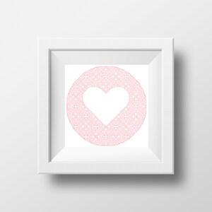 Può includere: Una cornice quadrata bianca con un disegno a forma di cuore rosa. Il cuore è circondato da un motivo circolare di vortici e forme intricate. L'opera d'arte è centrata su uno sfondo bianco.