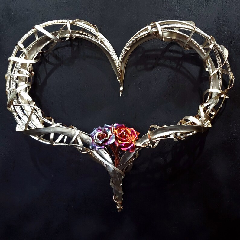May include: A silver metal heart-shaped sculpture with two iridescent roses at the bottom.