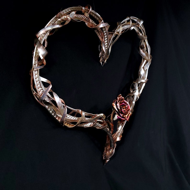 May include: A heart-shaped metal wreath with a rose design. The wreath is made of twisted copper wire and has a rustic, vintage look.