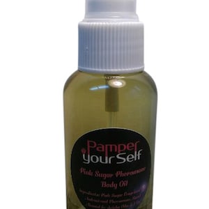 Może przedstawiać: Przezroczysta szklana butelka olejku do ciała z białą dyszą rozpylającą. Etykieta jest czarna ze słowami "Pamper your Self" i "Pink Sugar Pheromone Body Oil". Olejek w środku ma jasny bursztynowy kolor.