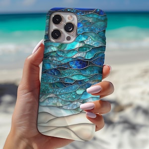 以下が含まれることがあります： 青と白の色合いの海の波のモザイクデザインのスマートフォンケース。ケースは光沢のある仕上がりと保護設計になっています。ケースはビーチの背景の前に保持されています。