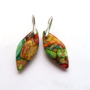 Puede incluir: Un par de pendientes con un gancho plateado y una piedra colorida, abstracta, en forma de lágrima.