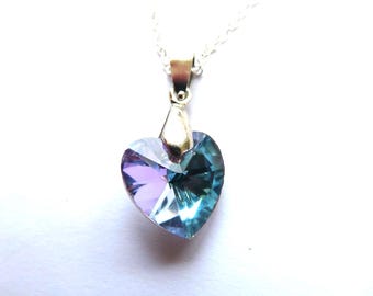 May include: A heart-shaped pendant necklace with a silver chain. The pendant is a faceted crystal, displaying shades of purple and teal. The pendant is attached to a silver-colored metal bail.