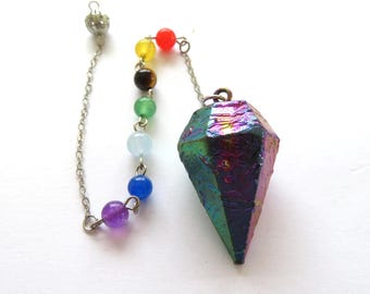 Op de afbeelding: Een pendel met een facetgeslepen, iriserende kristallen punt. Een ketting verbindt het kristal met een reeks kleurrijke kralen, waaronder rood, geel, groen, blauw en paars. De pendel is ontworpen voor spirituele praktijken.