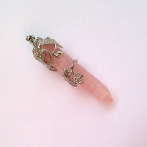 May include: A pink rose quartz crystal pendant with a silver floral design. The pendant is a long, pointed crystal with a silver bail at the top.