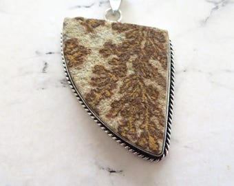 May include: A silver pendant with a triangular shaped stone featuring a brown and white dendritic agate pattern.