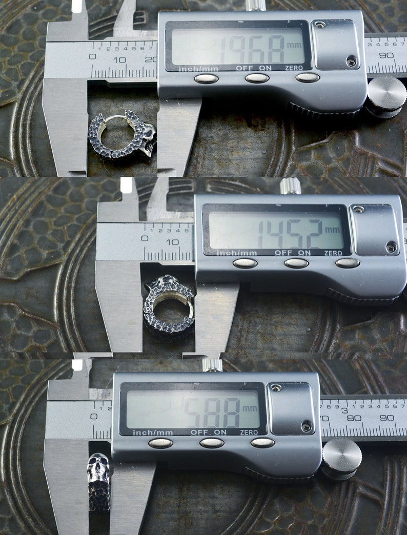 K&ouml;nnte beinhalten: Ein silberner Totenkopf-Hoop-Ohrring, der mit einer digitalen Schieblehre gemessen wird. Die Schieblehre zeigt 196,8 mm, 145,2 mm und 588 mm an.