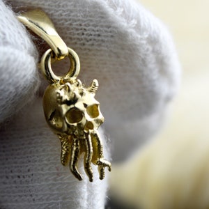 Op de afbeelding: Gouden hanger met een gedetailleerde schedel met tentakels, een populair ontwerp voor sieraden.