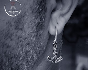 May include: Silver earring with a hammered axe pendant. The earring is hanging from a person's ear.