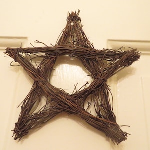 May include: A brown twig star-shaped wreath with a wire loop for hanging.
