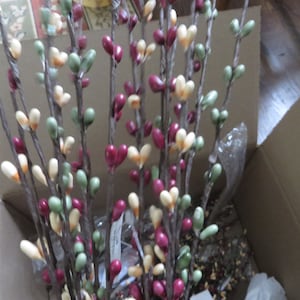 May include: A collection of decorative branches with heart-shaped ornaments in shades of red, green, and cream. The branches are brown and appear to be made of a natural material. The ornaments are clustered along the branches, creating a visually appealing display.
