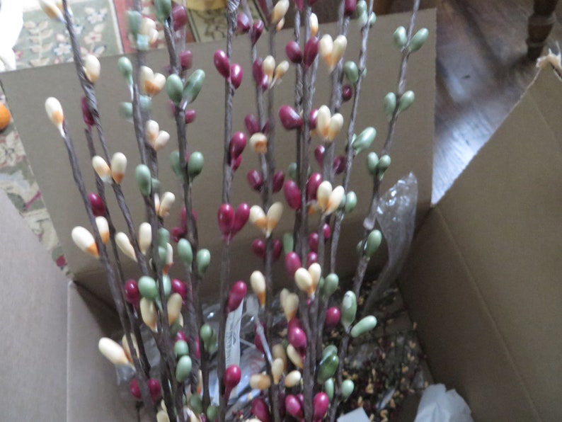 May include: A collection of decorative branches with heart-shaped ornaments in shades of red, green, and cream. The branches are brown and appear to be made of a natural material. The ornaments are clustered along the branches, creating a visually appealing display.