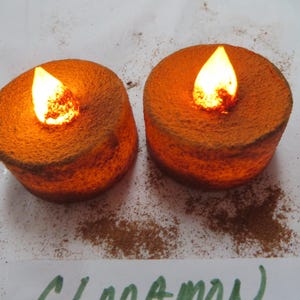 May include: Two orange battery-operated tea light candles with a flickering flame effect.