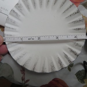 May include: White round plate with a scalloped edge and a black distressed finish. The plate is 4 inches in diameter.