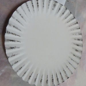 May include: White round paper plate with a black scalloped edge.