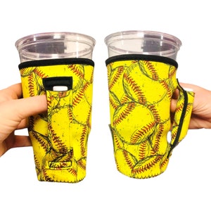 Puede incluir: Dos portavasos de neopreno amarillo y negro con un patrón de softball. Un portavasos tiene un asa y el otro una correa.