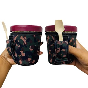May include: Two insulated cup holders with a camouflage pattern. Each holder has a slot for a spoon or straw. The holders are made of a soft, flexible material and are designed to keep drinks cold or hot.