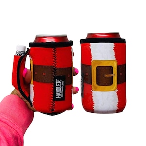 May include: Two red can coolers designed to look like Santa Claus suits. Each cooler has a black top, a brown belt with a gold buckle, and white trim. One cooler has a handle with a white and black pattern. The text "HANDLER" is visible.