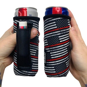May include: A black and white can cooler with a red, white, and blue American flag design and a red line running horizontally across the flag. The cooler has a black handle with a pocket for a small item. The text "HANDLEK" is printed on the cooler.