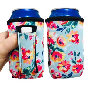 May include: Two blue and black can coolers with a floral pattern. The coolers have a handle and a slot for a credit card. The pattern is a light blue background with pink, yellow, and green flowers.