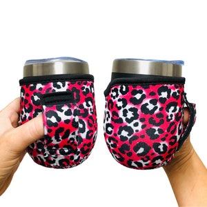 Puede incluir: Dos portavasos de neopreno con estampado de leopardo rosa y negro con asa negra. Un portavasos tiene un agujero para el dedo para facilitar su transporte.