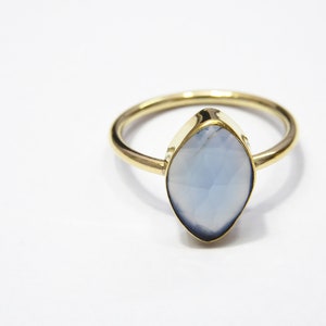 Op de afbeelding: Een gouden ring met een lichtblauwe edelsteen. De edelsteen heeft een marquise-vorm en een facetgeslepen.