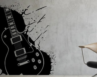 May include: Black and white silhouette of an electric guitar with splatter paint design on a gray wall. A black and silver office chair with a wooden seat is in the foreground.