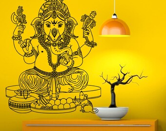 May include: Black and white line art illustration of the Hindu deity Ganesha, sitting on a platform with offerings. The background is a yellow wall with a hanging light fixture.
