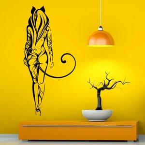 May include: Black and white silhouette of a woman with a floral design on a yellow wall. A small bonsai tree sits on a shelf below the wall art.