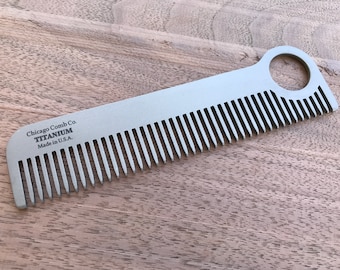 May include: A silver titanium comb with a hole in the handle. The comb is engraved with the text "Chicago Comb Co. TITANIUM Made in U.S.A."