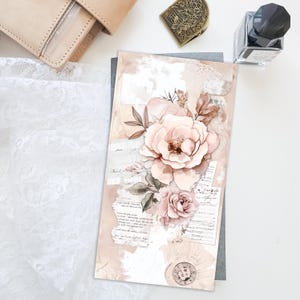 May include: A decorative art print with a large, pale pink rose and smaller roses, combined with vintage paper and script details. The print has a soft, watercolour style and a neutral colour scheme. A leather journal and ink bottle are also visible.