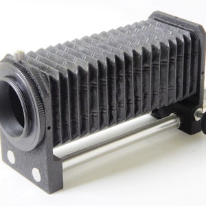 May include: Black bellows camera extension tube with a silver metal focusing rail and a black knob labeled "PUSH FOCUS".