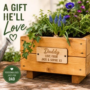 May include: A wooden planter box filled with plants and flowers, including blue grape hyacinths and purple anemones. The box has a wooden plaque that reads "Daddy LOVE FROM JACK & SOPHIE XX". The image includes the text "A GIFT HE'LL Love" and "PERSONALISED JUST FOR DAD".