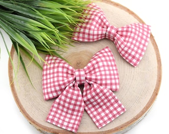 Op de afbeelding: Twee roze en witte gingham strikjes op een houten oppervlak.
