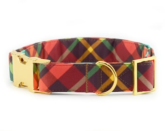 May include: A red, brown, yellow, and green plaid dog collar with gold hardware. The collar has a buckle and a D-ring.