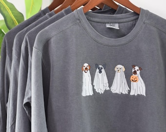 Puede incluir: Sudadera gris con un diseño de temática de Halloween con cuatro perros disfrazados de fantasmas. Tres de los perros llevan disfraces de fantasmas blancos, mientras que el cuarto perro lleva un disfraz de fantasma con una calabaza.