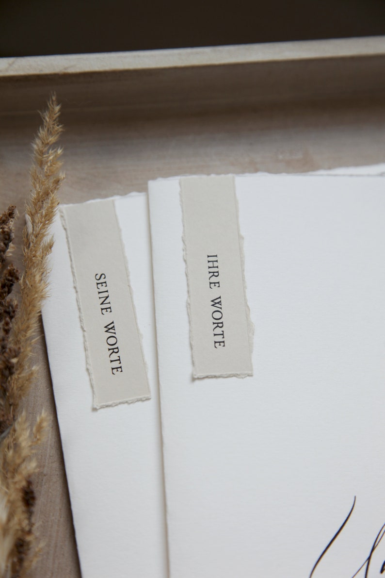 Peut inclure: Deux cartes blanches aux bords d&eacute;chir&eacute;s, chacune avec une &eacute;tiquette beige. L'&eacute;tiquette de gauche indique "SEINE WORTE" et l'&eacute;tiquette de droite indique "IHRE WORTE".