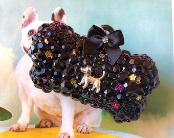 May include: A black jeweled dog bone charm with a silver dog silhouette and a black bow. The charm is decorated with rhinestones and colorful accents.