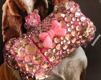May include: A pink USB flash drive encrusted with sparkling rhinestones and a pink bow. The flash drive has a dog bone charm and is set against a background with a dog.