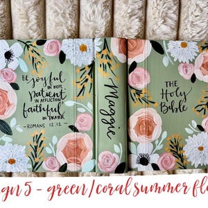 May include: A green Bible cover with coral, white, and yellow floral patterns. The cover has the text "Be joyful in hope, patient in affliction, faithful in prayer - Romans 12:12" and "The Holy Bible". The name "Maggie" is written on the spine.